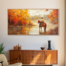 Load image into Gallery viewer, Cowboy sitting by campfire near a lake in the woods with autumn leaves, Framed Canvas Print, moody fall wall art, rustic western home decor