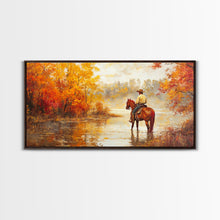 Load image into Gallery viewer, Cowboy sitting by campfire near a lake in the woods with autumn leaves, Framed Canvas Print, moody fall wall art, rustic western home decor
